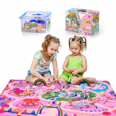 Two young girls sitting on the Rainbow Unicorn Activity Play Mat with the play mat packaging in the background.